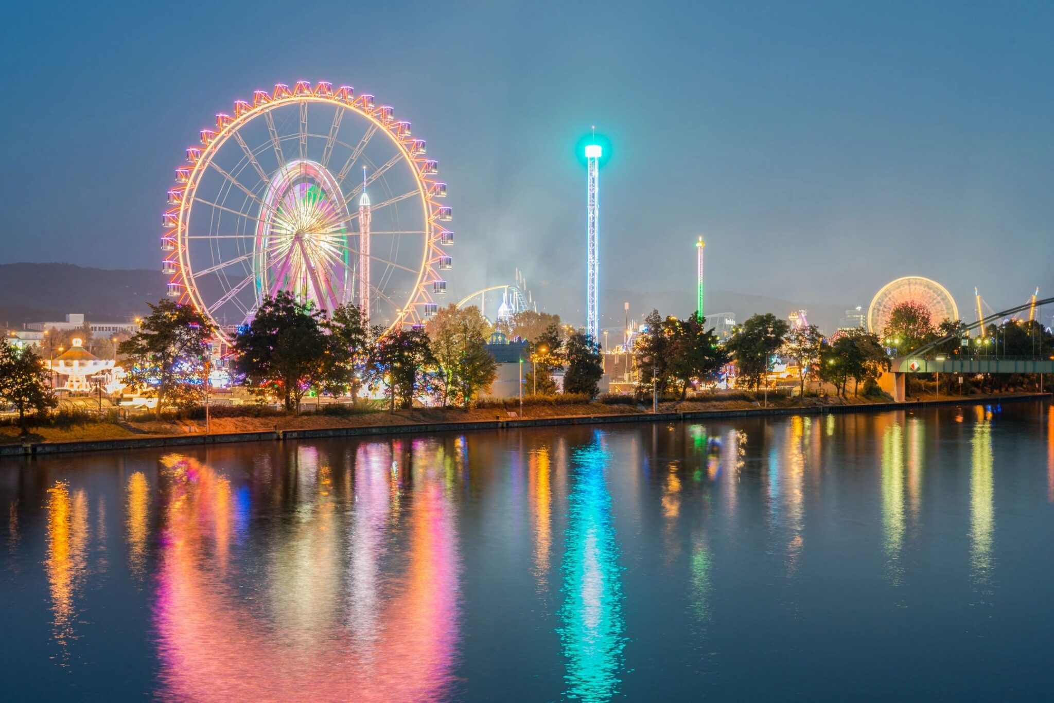 Illuminated theme park rides reflected on the water at night